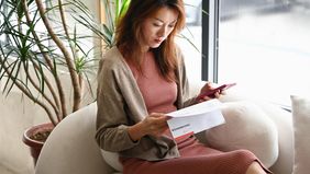 Woman checking her bank statements on a sofa