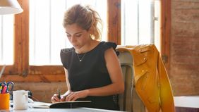 Young woman learning how to manage money in her notebook