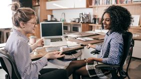 Two women talking in a networking space.
