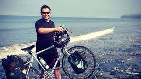 Man and bike on a beach after he quit his job to travel full-time