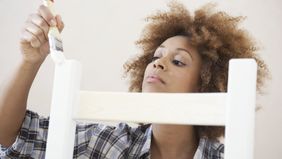 A woman painting a chair white