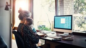 Mom working at home while holding a child.