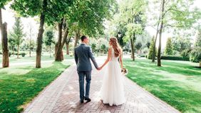 Happy couple walking down a path after their wedding