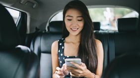 Woman in Taxi trying to figure out how much to tip her driver.