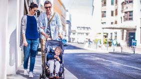 parents pushing toddler in stroller along sidewalk