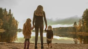Mother and her daughters looking at a lake.