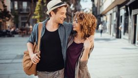 couple walking on street with arms around each other
