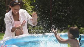 A woman plays with her child in a kiddie pool