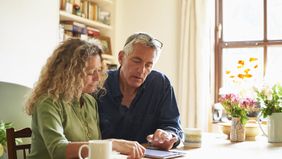 Couple looking at tablet and discussing the high cost of health care in retirement.