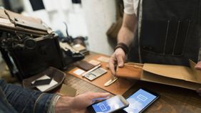 A customer uses smartphone to make a cashless purchase at small business