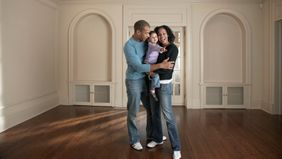couple holding baby girl in a room while house hunting