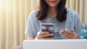 Woman holding mobile phone with credit card pondering credit report and score.