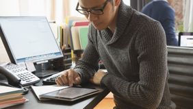 Man looking at tablet researching the difference between group disability insurance and individual disability insurance.