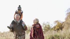 Man and woman walking with their grandchild as they discuss the pros and cons of gifting an estate before death