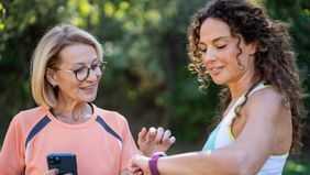 Two women talking and jogging in the public park. 
