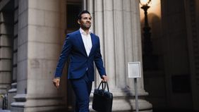 Professional businessman walking confidently with briefcase in city