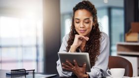 Woman looking at a tablet and learning about investing in your 20s