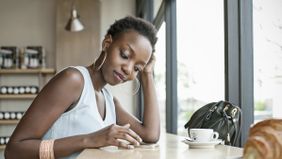 Woman sitting at a table and drinking coffee while learning about the basics of investing