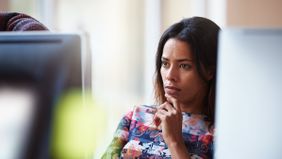 Woman looking at a computer screen, researching brokerage accounts.