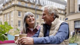 A happy senior couple enjoying a moment together seated at an outdoor city cafe.