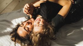 Happy mother and daughter having fun and playing together on the bed at home.