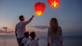 Family releasing paper lanterns by the sea