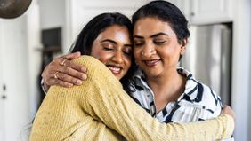 Mother embracing adult daughter at home