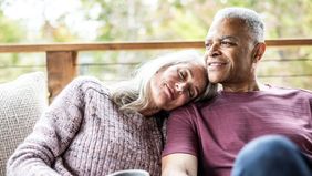 Couple having coffee and embracing on back porch of vacation home - stock photo