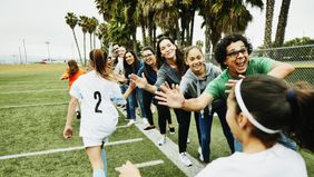 Young female soccer players high fiving parents on sidelines after soccer game