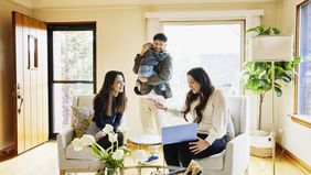 Wide shot of family discussing home for sale with real estate agent