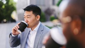usinessman enjoys coffee in a sunlit courtyard outside modern office