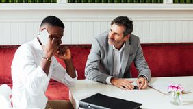 Businessmen discuss markets and economy between meetings in a modern coffee shop 