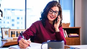 Woman financial advisor talking on the phone and taking notes