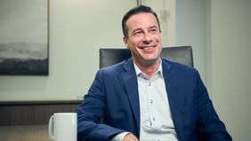 Male advisor, businessperson smiling at desk