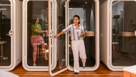 Co-workers use private booths in modern office