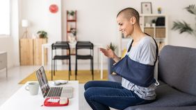 Woman in an arm sling using a laptop for a video call