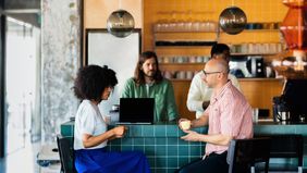 Co-workers Chatting Over Coffee at Modern Cafe Counter 