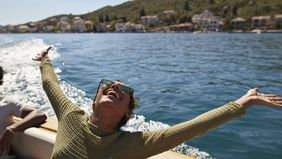Happy woman with arms raised in motorboat