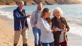couple-walking-on-beach-with-adult-offspring