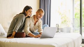 Shot of smiling couple planning finances on laptop