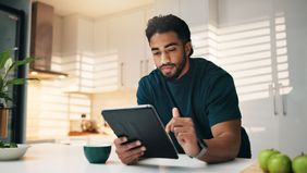 Man in kitchen in morning reading this week’s Market Commentary