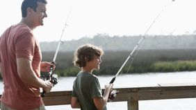 Dad fishing with son and wondering how tariffs will affect the economy.
