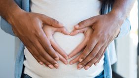 couples' hands on pregnant belly