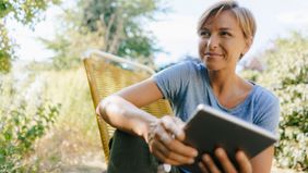 Woman sitting outdoors using a tablet