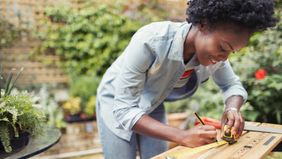 Young woman measures wood for renovation project. 