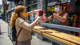 Restaurant owner serves customer at outdoor pick-up during pandemic