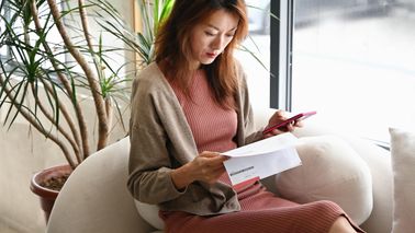 Woman checking her bank statements on a sofa