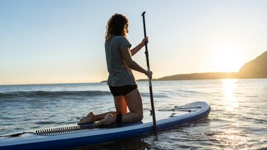 Woman paddleboarding at sunrise celebrating financial freedom with Northwestern Mutual