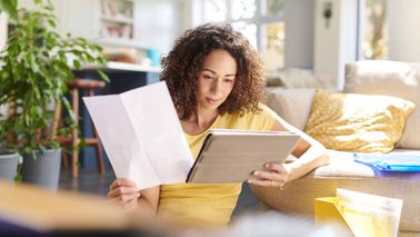 woman looking at tablet deciding to pay debt or start investing