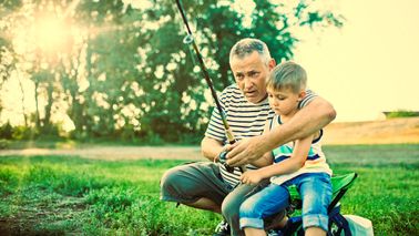 A grandparent and grandchild fish together at the lakeshore.
